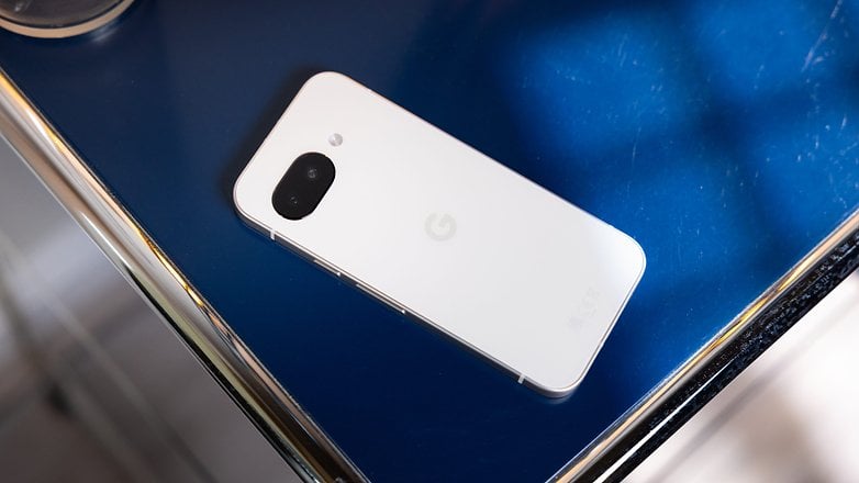 Um smartphone Google Pixel 9a repousado sobre uma superfície azul. Um smartphone Google Pixel 9a repousado sobre uma superfície azul.